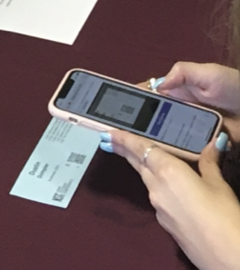 The QR code on a New Student Conference name tag is being scanned with a phone.